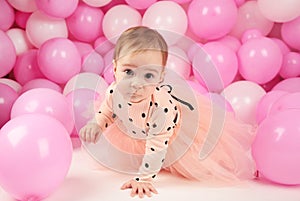 Baby girl celebrate her first birthday. Girl on background of pink balloons