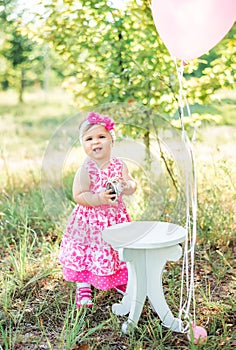 Baby girl celebrating her first bithday with gourmet cake and balloons