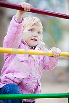 Baby girl on child's playground in spring time