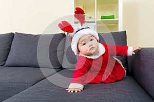 Baby girl with christmas dressing and crawling on sofa