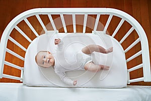 Baby girl in co-sleeper attached to parents` bed