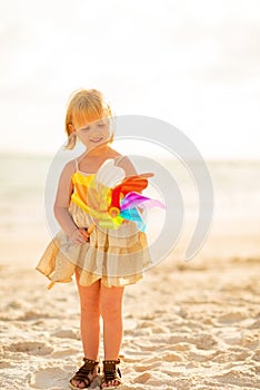 Baby girl with colorful windmill toy on beach