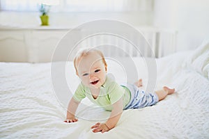Baby girl crawling on bed and laughing