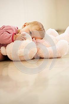 Baby Girl Cuddling Pink Teddy Bear At Home