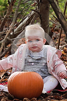 Baby girl cute face blonde hair in autumn leaves during holiday season