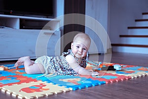 Baby girl doing tummy time on colorful play mat photo