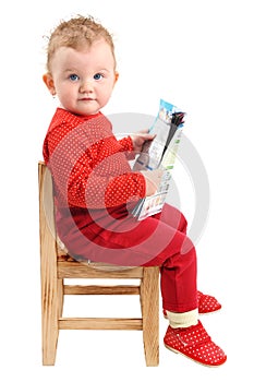 Baby girl dressed in red sitting on chair reading