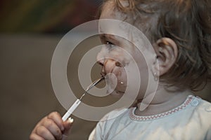 baby girl eating her chocolate desert with a spoon and making a mess