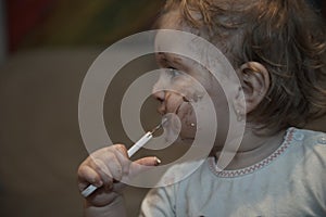 baby girl eating her chocolate desert with a spoon and making a mess