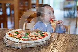 Baby girl eating pizza in italian restaurant, Healthy, unhealthy food, children`s fast food.