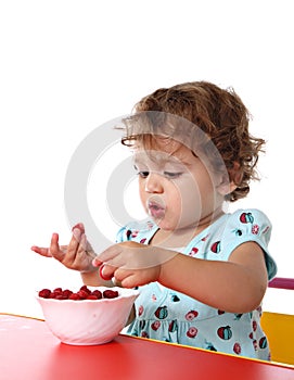 Baby girl eating raspberry