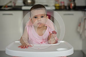 Baby girl eating strawberry on highchairs