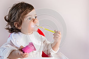 Baby girl eating yogurt with messy face