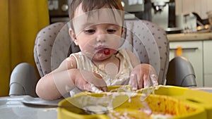 baby girl eats dirty. happy family kid a dream concept. baby funny got dirty in yogurt dairy product all over his face