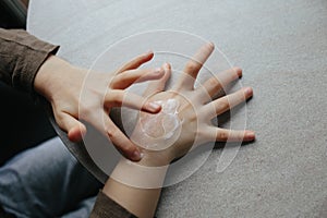 Baby girl finger applying moisturizing cream on hand. Care about children clean and soft body skin. Top view. Closeup