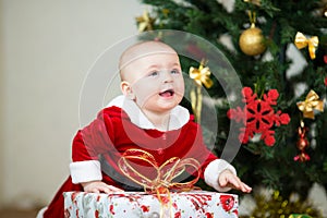 Baby girl in front of Christmas tree with gift