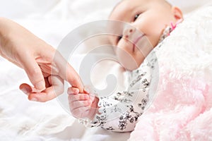 Baby girl grasping her parents finger