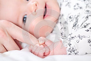 Baby girl grasping her parents finger