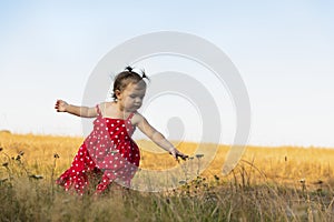 Baby girl have fun in the meadow, running barefoot on the green grass