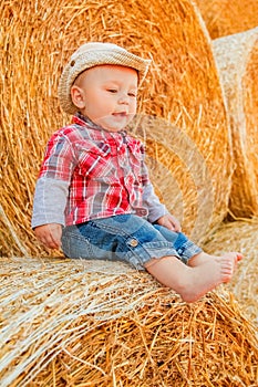 A Baby girl on a haystack happy on the field. Background with children a joyful childhood