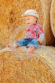A Baby girl on a haystack happy on the field. Background with children a joyful childhood