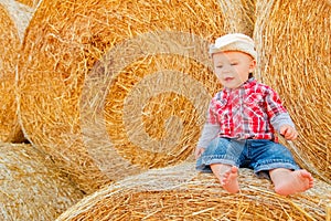 A Baby girl on a haystack happy on the field. Background with children a joyful childhood