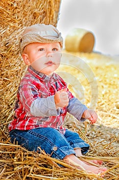 A Baby girl on a haystack happy on the field. Background with children a joyful childhood