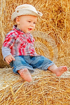 A Baby girl on a haystack happy on the field. Background with children a joyful childhood