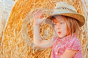 A Baby girl on a haystack happy on the field. Background with children a joyful childhood