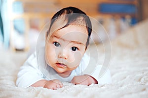 Baby girl on her stomach. Looking up with surprised expression.