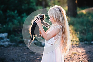 Baby girl holding hands a kitten in the light of sunset