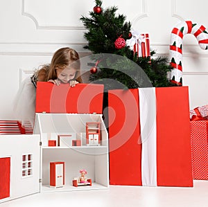 Baby Girl Kid playing with christmas red house in play room at home or kindergarten with little dolls toys