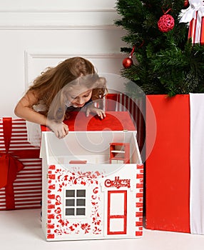 Baby Girl Kid playing with christmas red house in play room at home or kindergarten with little dolls toys