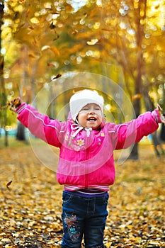 Baby girl laughing and playing in the autumn