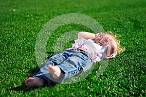 Baby girl laying on the green grass in the park