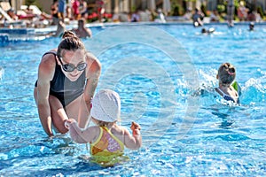 Baby girl learn to swim in pool with her mother