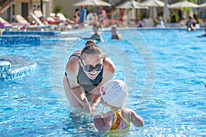 Baby girl learn to swim in pool with her mother