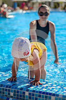 Baby girl learn to swim in pool with her mother