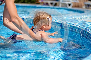 Baby girl learn to swim in pool with her mother