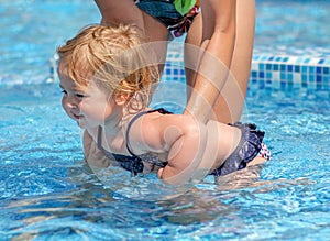 Baby girl learn to swim in pool with her mother