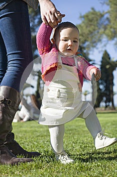 Baby girl learning to walk at grass park