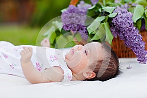 Baby girl with lilac bouquet in basket