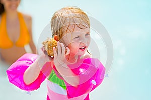 Baby girl listening sound of sea in shell