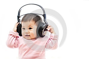 A baby girl listens music with headphone with hands