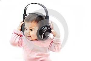 A baby girl listens music with headphone with hands