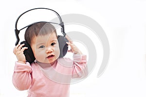 A baby girl listens music with headphone with hands