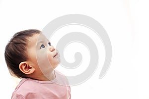 A baby girl looks up with pink clothes, not looking camera