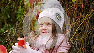 Baby girl lying on autumn leaves in pink coat