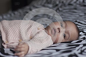 Baby girl lying on bed looking in the camera with beautiful eyes