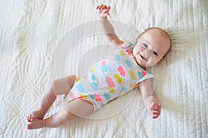 Baby girl lying on bed in nursery